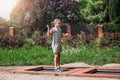 Little girl  is jumping on trampoline in a park. Happy laughing kid outdoors in the yard on summer vacation. Jump high Royalty Free Stock Photo