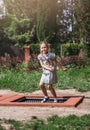 Little girl  is jumping on trampoline in a park. Happy laughing kid outdoors in the yard on summer vacation. Jump high Royalty Free Stock Photo