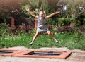 Little girl  is jumping on trampoline in a park. Happy laughing kid outdoors in the yard on summer vacation. Jump high Royalty Free Stock Photo