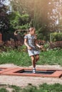 Little girl  is jumping on trampoline in a park. Happy laughing kid outdoors in the yard on summer vacation. Jump high Royalty Free Stock Photo