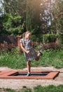 Little girl  is jumping on trampoline in a park. Happy laughing kid outdoors in the yard on summer vacation. Jump high Royalty Free Stock Photo