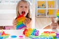 Little girl,kid,child plays with colorful pop it children`s room, bedroom.Funny trendy silicone antistress colorful sensory push