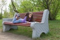 Little girl kid reading a book lying on a bench in spring park Royalty Free Stock Photo