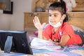 Little girl kid student raise her hand while studying online class with tablet at home, New normal.Covid-19 coronavirus.Social Royalty Free Stock Photo