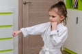 A little girl in a kimono goes in for sports - karate in her room.