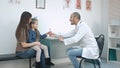 Little girl kissing her mom and smiling male doctor giving her candy for good behaviour Royalty Free Stock Photo