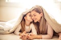 Little girl kissing her mother under blanket Royalty Free Stock Photo