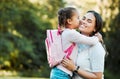 Little girl kissing her mother. Young mother hugging her daughter. Loving mother hugging daughter before school outside Royalty Free Stock Photo
