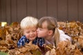 Little girl kissing a little boy laying in leaf pile leaves