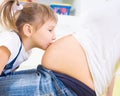 Little girl kissing pregnant belly