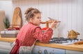 A little girl in the kitchen in an apron cooks something in a saucepan on a gas stove Royalty Free Stock Photo