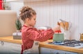 A little girl in the kitchen in an apron cooks something in a saucepan on a gas stove Royalty Free Stock Photo