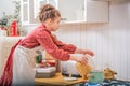 A little girl in the kitchen in an apron cooks something in a saucepan on a gas stove Royalty Free Stock Photo