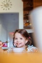 Little girl in the kitchen smiling, eating spaghetti