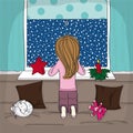 Little girl kneeling on the sofa looking out of the window to the night winter scenery