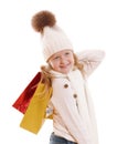 A little girl in a knitted hat with a pompon, scarf and sweater, is holding multicolored paper bags. Isolated on white background Royalty Free Stock Photo