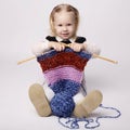 Little girl knitting scarf