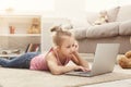 Cute little girl doing homework on laptop, sitting on the floor at home Royalty Free Stock Photo