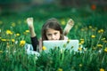 Little girl with laptop lying on green grass. Royalty Free Stock Photo