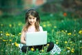 Little girl with laptop lying on outdoor at summer. Royalty Free Stock Photo