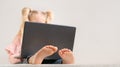 Little girl with laptop, only top of the blonde head and little feet are visible