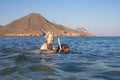Little girl laughing with diving glasses on back of woman snorkeling in the water of a beach in Andalusia Royalty Free Stock Photo