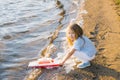 Little girl launches a toy boat into the lake