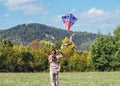 Little girl launching a colorful kite on the green grass meadow in the mountain fields. Happy childhood moments or outdoor time