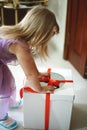 A little girl in a lavender dress opens a big gift
