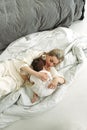 The little girl lay down on her mother and wants to sleep. Mom tenderly hugs her daughter