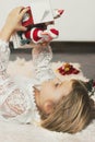 Little girl laying on the floor, playing with Christmas decoration, little Santa Claus coming out of the box Royalty Free Stock Photo
