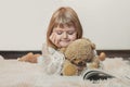 Little girl laying on the floor, reading book with her teddy bear, Christmas background Royalty Free Stock Photo