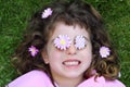 Little girl laying grass daisiy flowers in eyes