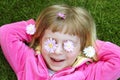 Little girl laying grass daisiy flowers in eyes