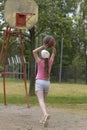 Little girl leaned back holding a basketball in her hands and aiming for a throw into the ring Royalty Free Stock Photo