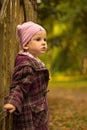 A little girl leaning against a gate in the park. Autumn colors Royalty Free Stock Photo