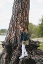 Little girl leaning against a large oak tree and looking at the camera Royalty Free Stock Photo