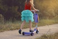 Little girl learn to ride scooter in a park on sunny summer day. Active leisure and outdoor sport for child. Royalty Free Stock Photo