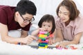 Little girl with learning disabilities Or the group of dow syndrome is learning about colorful wood toy with family teaching and