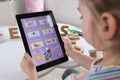 Little girl learning English with tablet indoors at online lesson, closeup Royalty Free Stock Photo