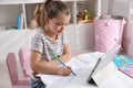 Little girl learning English with tablet indoors at online lesson Royalty Free Stock Photo