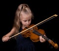 Little girl learning to play the violin isolated on black Royalty Free Stock Photo