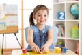 Little girl is learning to use colorful play dough in child room