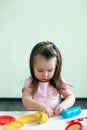 Little girl is learning to use colorful play dough indoor, concept of daycare activity Royalty Free Stock Photo