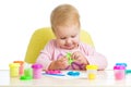 Little girl learning to use colorful play dough isolated on white background