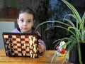 A little girl learns to play chess and demonstrates a magnetic chessboard with pleasure. Cultural leisure for children