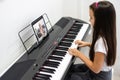 A little girl learns to play the piano from video lessons. Online distance learning during covid-19 Royalty Free Stock Photo