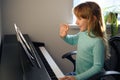 A little girl learns to play the piano from video lessons. Online distance learning during covid-19