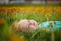 Little girl lies on the grass in a flower clearing in the summer.