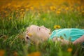 Cute little girl lies on the grass in a flower clearing in the summer